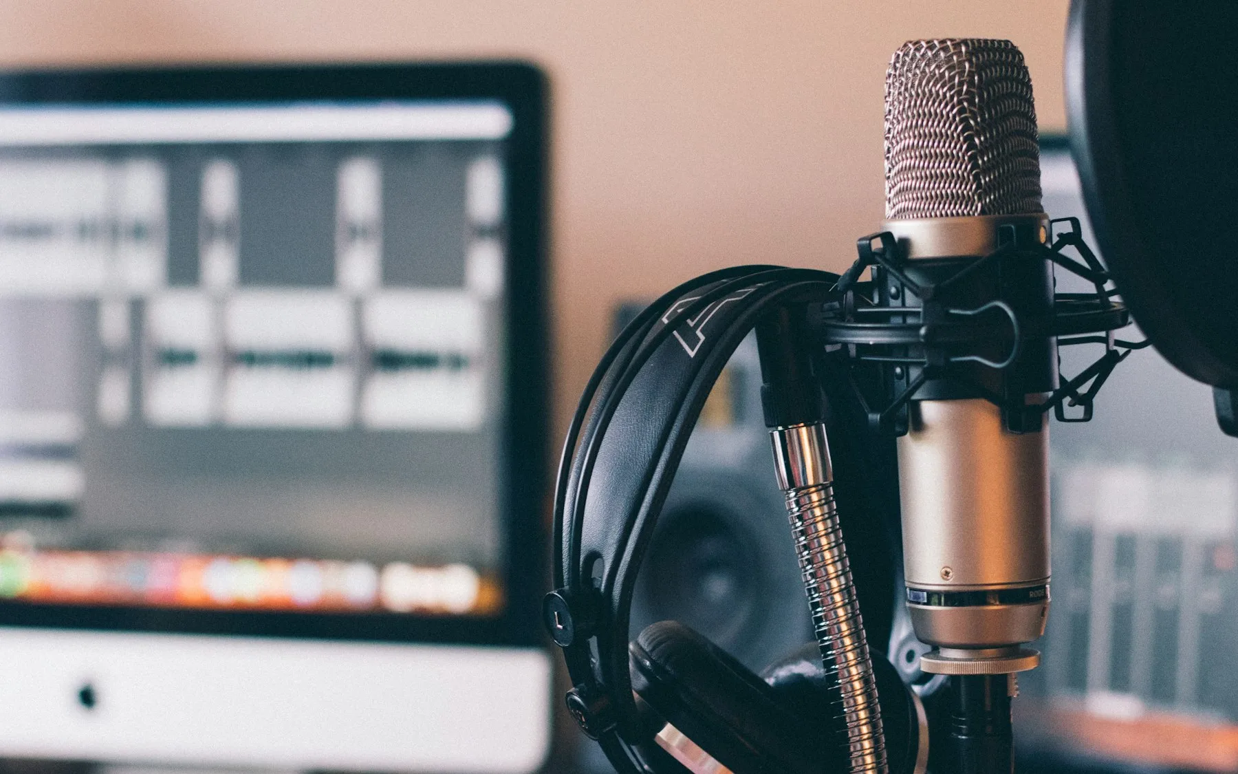 Birou de podcast: microfon pe stativ, căști și ecran de înregistrare